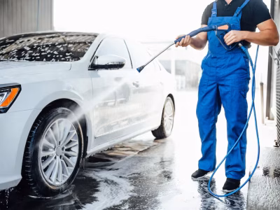 professional-washer-blue-uniform-washing-luxury-car-with-water-gun-open-air-car-wash_496169-333